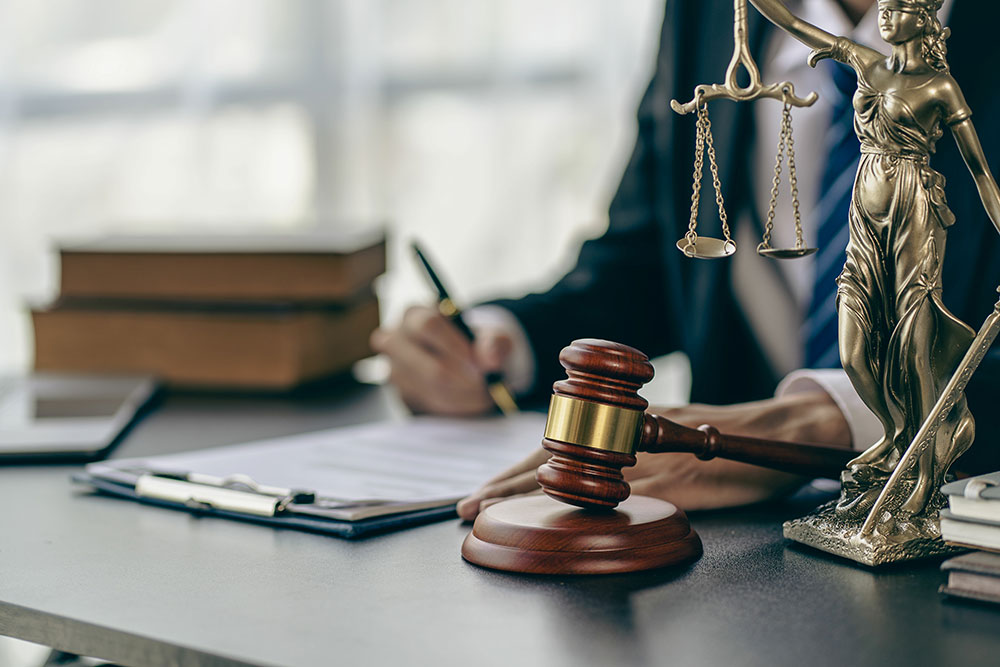 A lawyer from the Philadelphia and Conshohocken area sitting at a desk taking notes with a gavel and scales of justice in view